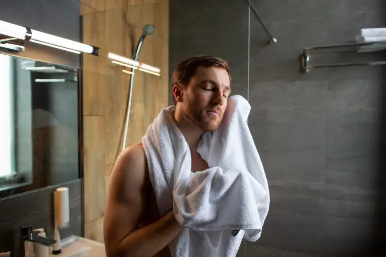 Mann trocknet sich im Bad die Haare mit einem Handtuch
