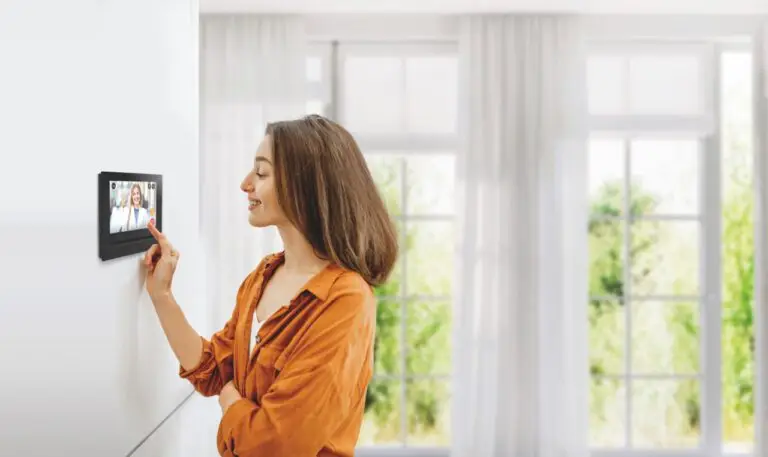 Frau bedient ein wandmontiertes Smart-Home-Panel am Fenster