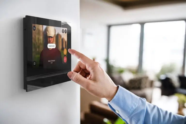 Hand bedient ein wandmontiertes Smart-Home-Tablet im Wohnzimmer