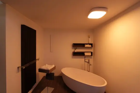 Wellnessbereich mit freistehender Badewanne und warmer Beleuchtung