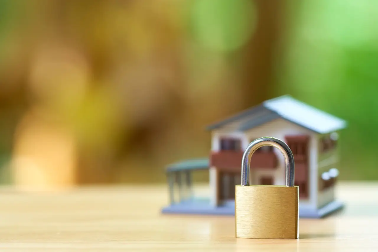 Modellhaus mit vorhängeschloss als symbol für smart-home-sicherheit